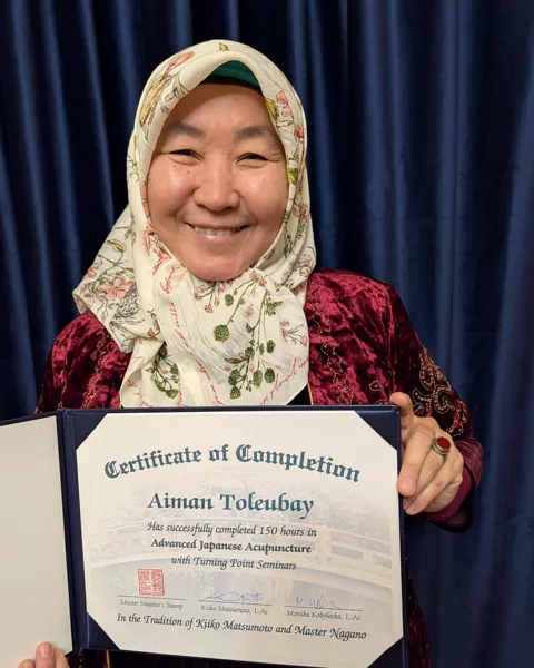 Dr Ayman Toleubay holding her certificate in Japanese acupuncture from the Kiiko Matsumoto tradition